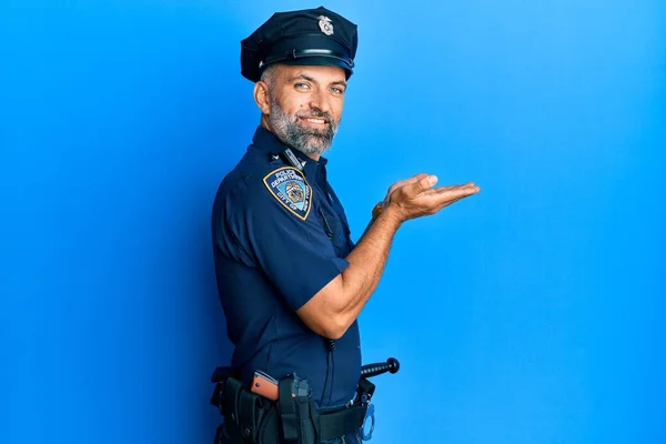 Middle age handsome man wearing police uniform pointing aside with hands open palms showing copy space, presenting advertisement smiling excited happy