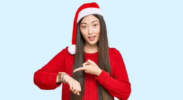 若いです中国の女性身に着けているクリスマスの帽子で急いで時間を見るために指す 動揺し 締め切り遅延のために怒っています — ストック写真
