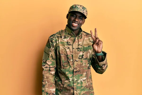 自信と幸せな笑顔ながら 若いアフリカ系アメリカ人の男は 軍の制服を着て指の数2で示すと指摘します — ストック写真