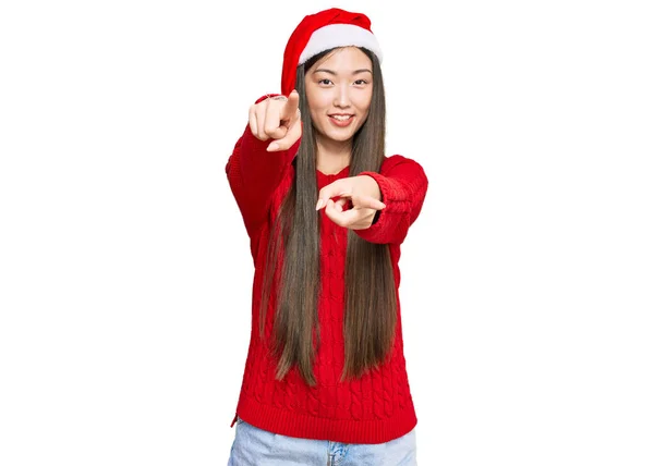 年轻的中国女人头戴圣诞礼帽 手指着你和相机 面带微笑 面带微笑 — 图库照片