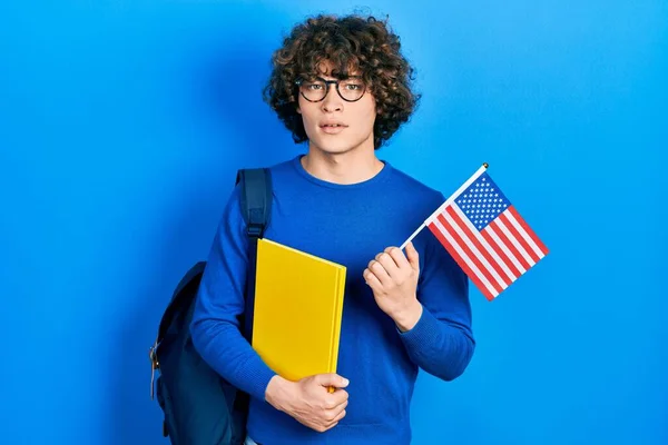 Guapo Joven Estudiante Intercambio Sosteniendo Bandera Expresión Despistada Confusa Concepto — Foto de Stock