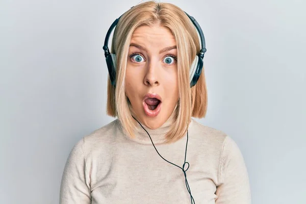 Молода Блондинка Слухає Музику Використовуючи Навушники Налякані Здивовані Відкритим Ротом — стокове фото