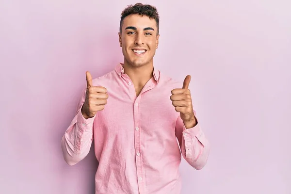 身穿休闲装的西班牙裔年轻人成功地做了一个积极的手势 竖起大拇指 笑容满面 快乐无比 快乐的表达和胜利的姿态 — 图库照片