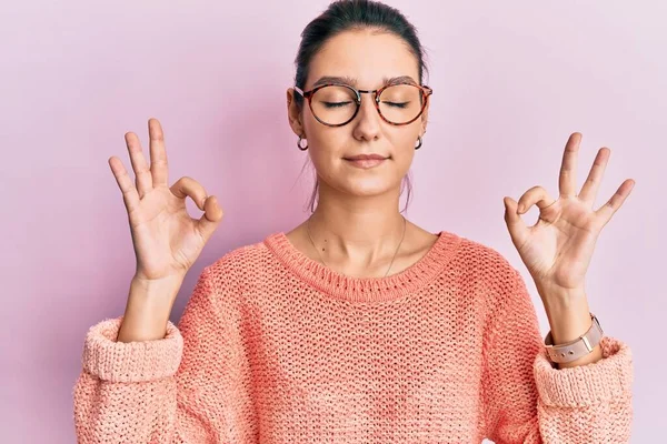 年轻的高加索女人穿着休闲装 戴着眼镜 闭着眼睛 微笑着 用手指做冥想动作 瑜伽概念 — 图库照片