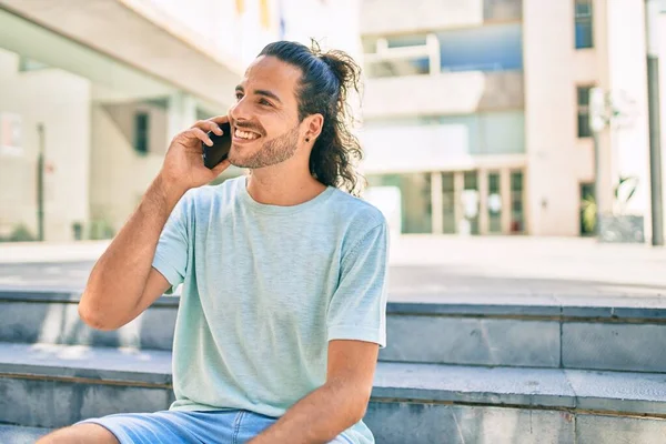 Genç İspanyol adam gülümsüyor. Şehirdeki akıllı telefondan konuşuyor..