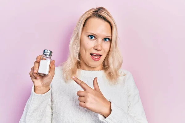 Beautiful Caucasian Blonde Woman Holding Salt Smiling Happy Pointing Hand — Stockfoto