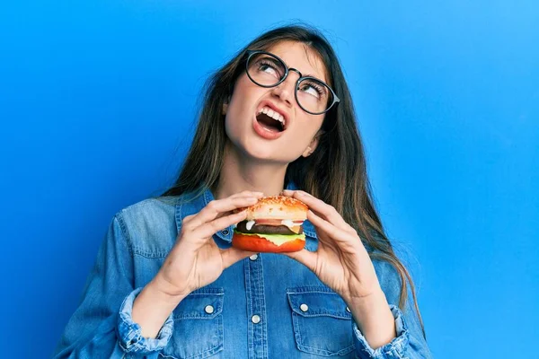 Young Caucasian Woman Eating Tasty Classic Burger Angry Mad Screaming — Stock Photo, Image