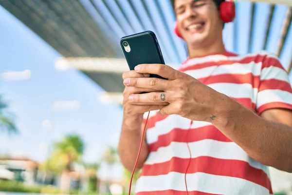 若い白人男性は 市内でスマートフォンやヘッドフォンを使用して幸せな笑顔 — ストック写真