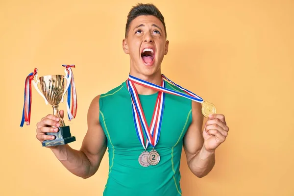 Jovem Menino Hispânico Segurando Troféu Campeão Vestindo Medalhas Irritado Louco — Fotografia de Stock