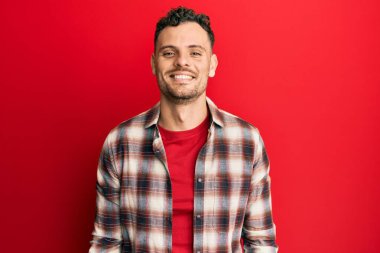 Yüzünde mutlu ve havalı bir gülümseme olan sıradan kıyafetler giyen genç İspanyol bir adam. şanslı kişi. 