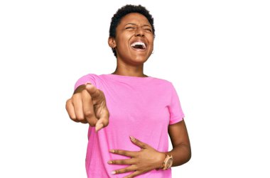 Genç Afro-Amerikan kadın, günlük kıyafetler giyip sana gülüyor, kamerayı işaret ediyor, yüzünü gösteriyor, utanç ifadesi. 