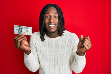 Elinde 100 dolarlık saç örgüsü olan Afrikalı Amerikalı adam gururla bağırıyor, zaferi ve başarıyı kutluyor. 