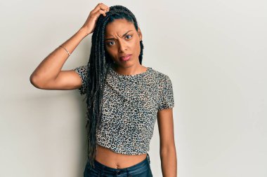 Günlük giysiler giyen Afrikalı Amerikalı bir kadın soru işaretlerini karıştırıyor ve merak ediyor. Şüpheyle kararsız, kafa kafaya düşünerek. Düşünceli kavram. 