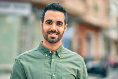 Genç İspanyol adam gülümseyerek şehirde mutlu mesut dikiliyor..