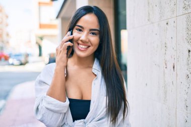 Genç İspanyol kız gülümsüyor. Şehirdeki akıllı telefondan konuşuyor..