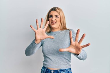 Günlük kıyafetler giyen, korku ifadesinden korkan beyaz bir kadın. El kol hareketi yapmayı kes, şok içinde bağır. panik konsepti. 