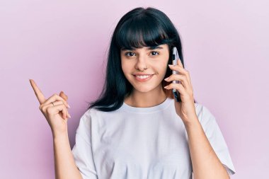 Genç İspanyol kız akıllı telefondan konuşuyor. Gülümsüyor, mutlu bir şekilde işaret ediyor. 