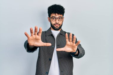 Sakallı, gözlüklü, korku ifadesinden korkan genç bir Arap. El kol hareketi yapmayı kes, şok içinde bağır. panik konsepti. 