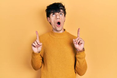 Yakışıklı hippi genç adam gündelik sarı süveter giyiyordu. Şaşırmış ve şaşırmıştı. Parmaklarıyla işaret ediyor ve kollarını kaldırıyordu.. 