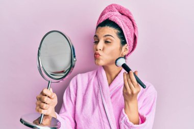 Duş bornozu giyen, makyaj fırçası kullanan, öpüşen, güzel ve seksi bir kadın. aşk ifadesi. 