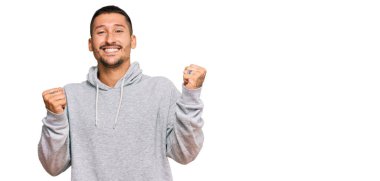 Dövmeli yakışıklı, sıradan bir kazak giyen gururlu, zaferi kutlayan ve kollarını kaldırarak heyecanlanan bir adam. 