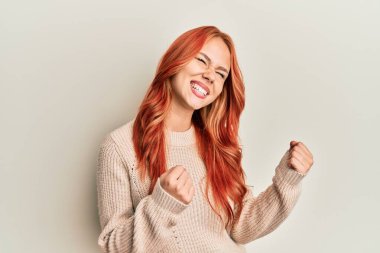 Genç, güzel, kızıl saçlı, sıradan bir kazak giyen, kolları havada, gözleri kapalı zaferi kutlayan bir kadın. Kazanan konsept. 