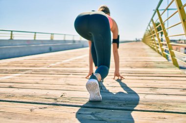 Koşu çizgisinde spor giysili genç sarışın kadın..