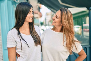 Güzel İspanyol anne ve kızı gülümseyerek şehirde mutlu mesut duruyorlar..