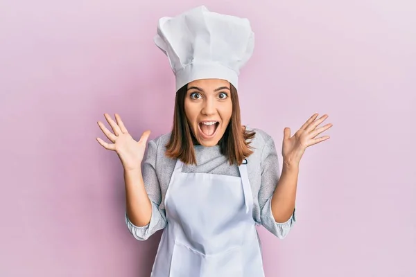 身穿职业厨师制服 头戴帽子的年轻漂亮女人 兴奋地举起双臂 睁开眼睛尖叫 庆祝着成功 获奖者概念 — 图库照片