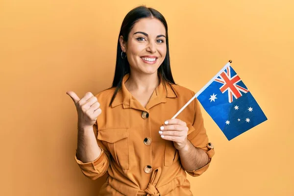 Young Brunette Woman Holding Australian Flag Pointing Thumb Side Smiling — ストック写真