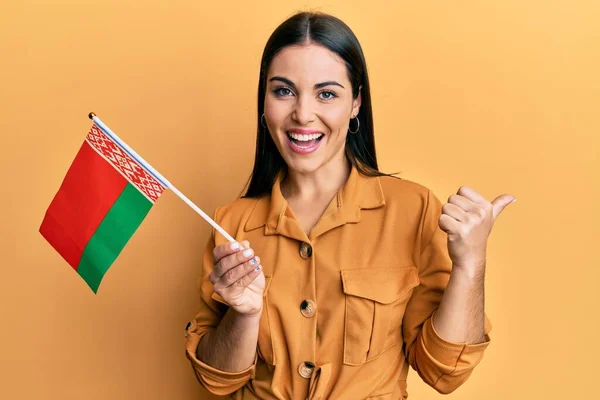 Young Brunette Woman Holding Belarus Flag Pointing Thumb Side Smiling — Fotografia de Stock