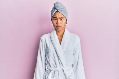 Duş havlusu şapkası ve bornoz giyen genç Çinli kadın şüpheci ve gergin, sorun yüzünden surat asıyor. negatif kişi. 