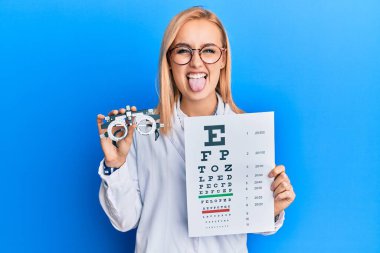 Güzel beyaz gözlüklü kadın elinde optometri gözlüğü ve sağlık muayenesi ile komik bir ifadeyle dilini dışarı çıkartıyor.. 