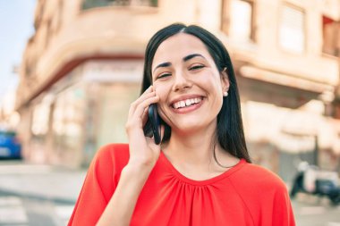 Genç Latin kız gülümsüyor. Şehirdeki akıllı telefondan konuşuyor..