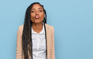 African american woman wearing business jacket looking at the camera blowing a kiss on air being lovely and sexy. love expression. 