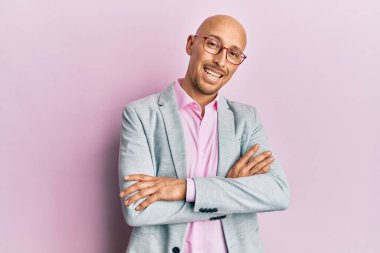 İş kıyafetleri ve gözlüklü kel adam kollarını kavuşturup kameraya bakarken gülümsüyor. pozitif kişi. 