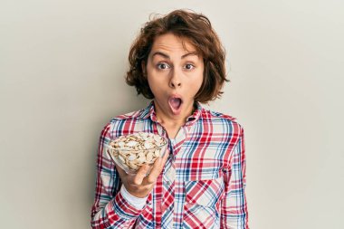 Genç esmer kadın elinde balkabağı tohumlarıyla dolu bir kâse tutuyor. Şaşırtmak için ağzı açık kalmış, inançsız bir yüz. 