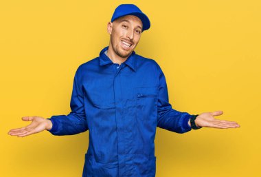 Sakallı, inşaatçı tulumu giymiş, kel bir adam. Gülümsüyor, avuçlarını açıyor, sunuyor, reklam yapıyor, karşılaştırıyor ve dengede duruyor. 