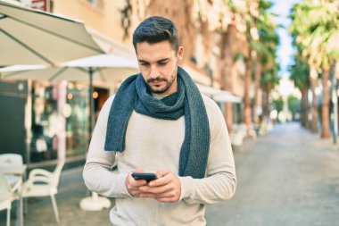 Şehirde akıllı telefon kullanan ciddi bir suratı olan genç bir İspanyol..