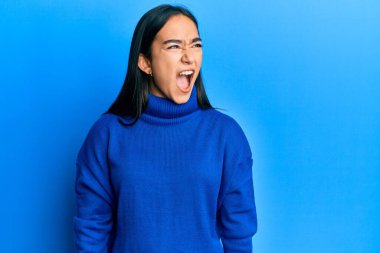 Asyalı genç bir kadın, sıradan bir kazak giyiyor kızgın ve kızgın bağırıyor sinirli ve öfkeli, öfkeyle bağırıyor. öfke ve agresif konsept. 