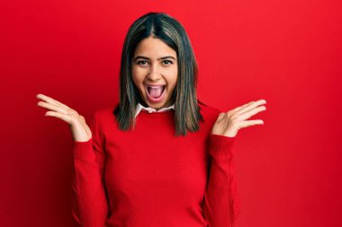 Genç Latin kadın gündelik giysiler giyip çılgınlığı kutluyor ve başarıya hayret ediyor. Kolları açık, gözleri açık heyecanla haykırıyor. Kazanan konsept 