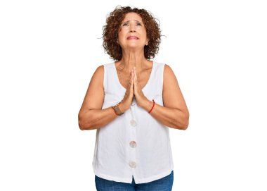 Güzel, orta yaşlı, olgun bir kadın, günlük beyaz tişörtler giyip, elleri bağlı yalvarıyor ve dua ediyor. Yüzünde umut ifadesi var. Çok duygusal ve endişeli. Yalvarıyor. 