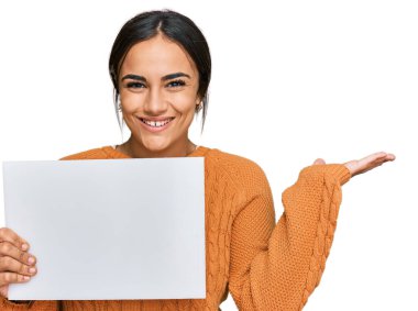 Genç esmer kadın boş afiş tutuyor zaferi mutlu bir gülümsemeyle ve kazanan yüz ifadesiyle kutluyor. 