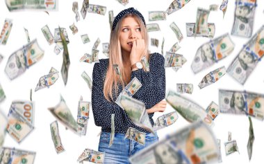 Genç, sarışın, sıradan kıyafetler giyen gergin ve gergin görünen elleri ağızdan tırnak yiyen genç bir kadın. anksiyete.