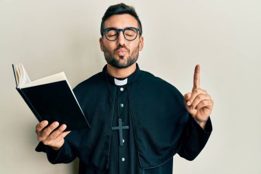 Genç İspanyol rahip elinde İncil 'le kameraya bakıp öpücükler savuran sevimli ve seksi. aşk ifadesi. 