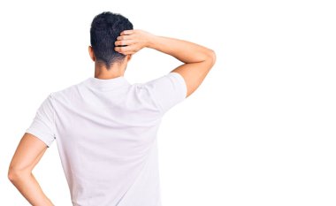 Genç, yakışıklı İspanyol bir adam günlük kıyafetlerini ters giyip elleri kafasında şüpheyi düşünüyor. 