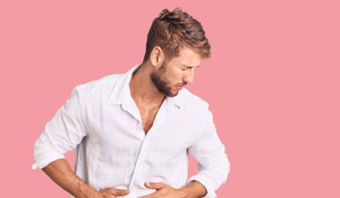 Genç, beyaz bir adam midesi üstünde gündelik kıyafetler giyiyor çünkü hazımsızlık, acı verici bir hastalık kendini iyi hissetmiyor. Ağrı kavramı. 