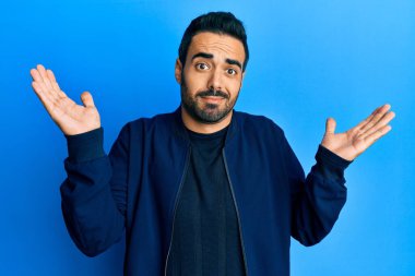 Gündelik kıyafetler giyen genç İspanyol adam habersiz ve kolları açık, hiçbir fikri ve şüpheli bir yüzü var.. 