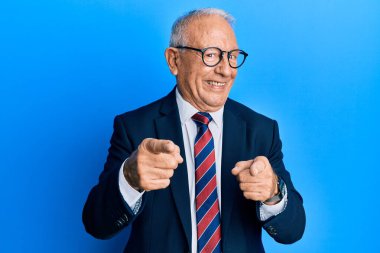 Beyaz üst düzey takım elbiseli ve kravatlı bir adam mutlu ve komik yüzüyle kamerayı işaret ediyor. iyi enerji ve titreşimler. 