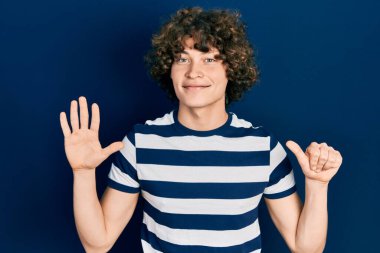 Yakışıklı, çizgili tişört giyen altı numarayı gösteren ve gülümseyen, kendinden emin ve mutlu bir genç.. 
